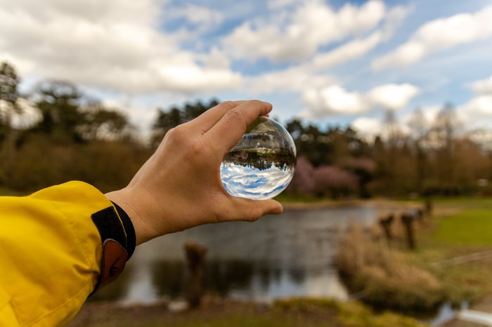 hand-holding-glass-sphere-nature